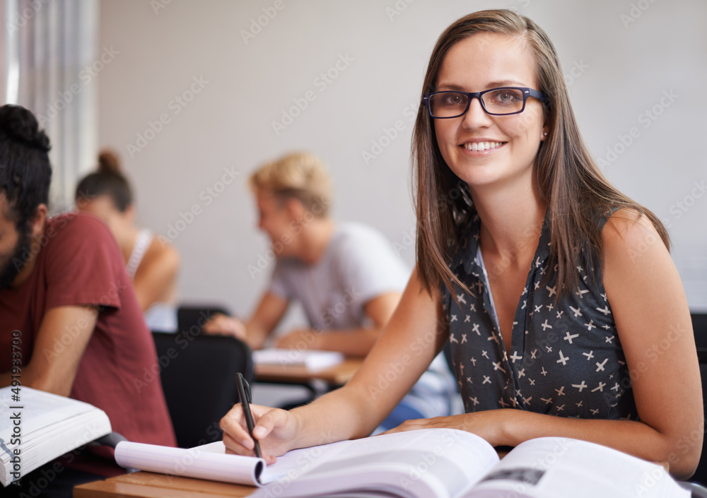 Theres nothing more important to me than education. An attractive young varsity student sitting in a classroom with a textbook in front of her.