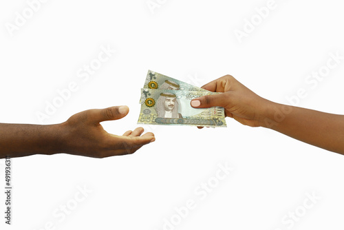 Hand giving 3D rendered 20 Bahrain Dinar notes to another hand. Hand receiving money © RODWORKS