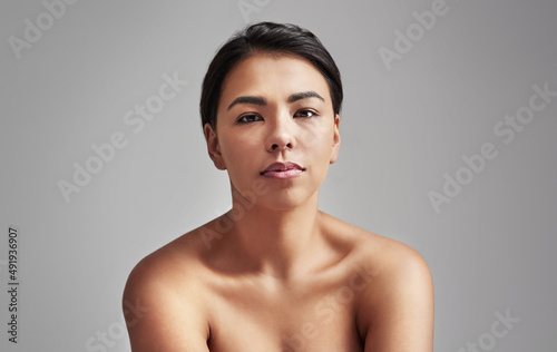 Naturally gorgeous. Studio shot of a young woman with wet hair posing against a gray background.