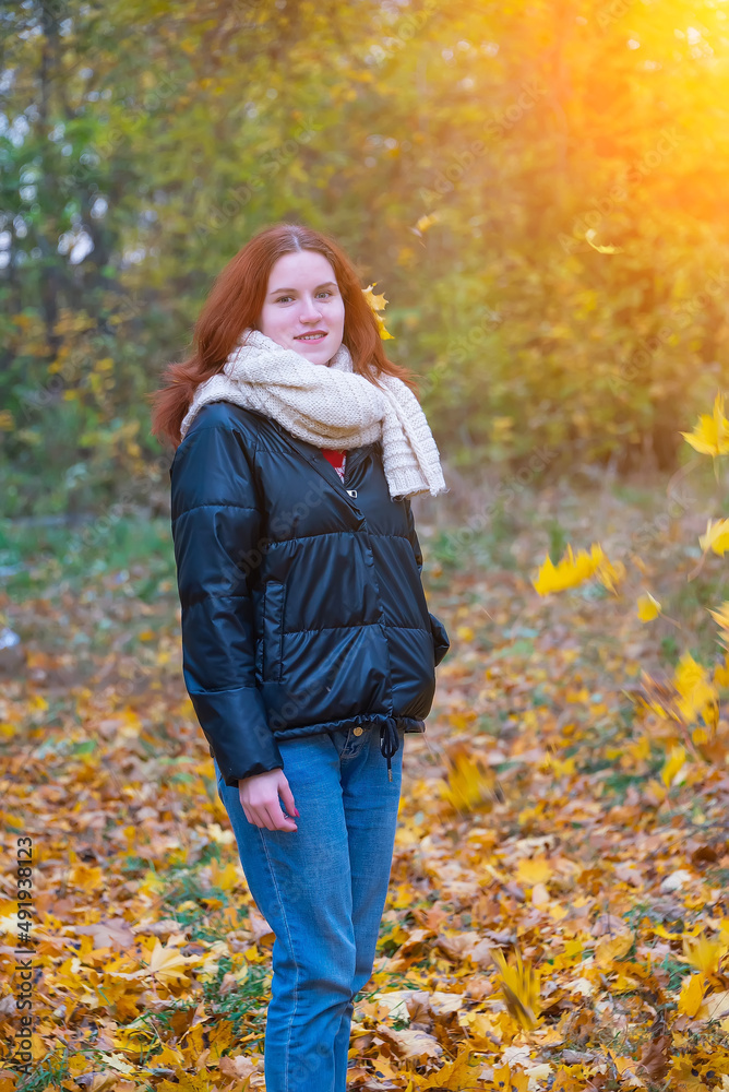 a portrait of a red - haired smiling girl in a jacket and scarf with her hair loose in full growth walks in the park . against the background of autumn nature, the concept of human emotion a portrait of a red - haired smiling girl in a jacket and scarf with her hair loose in full growth walks in the park . against the background of autumn nature, the concept of human emotion