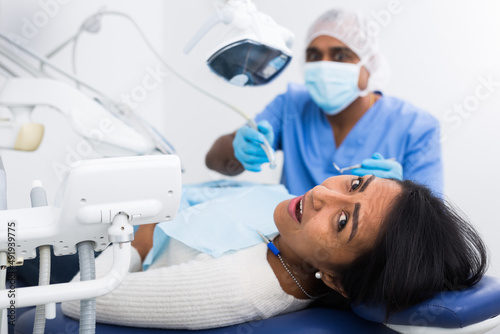 Dentist checking teeth of patient woman sitting in medical center