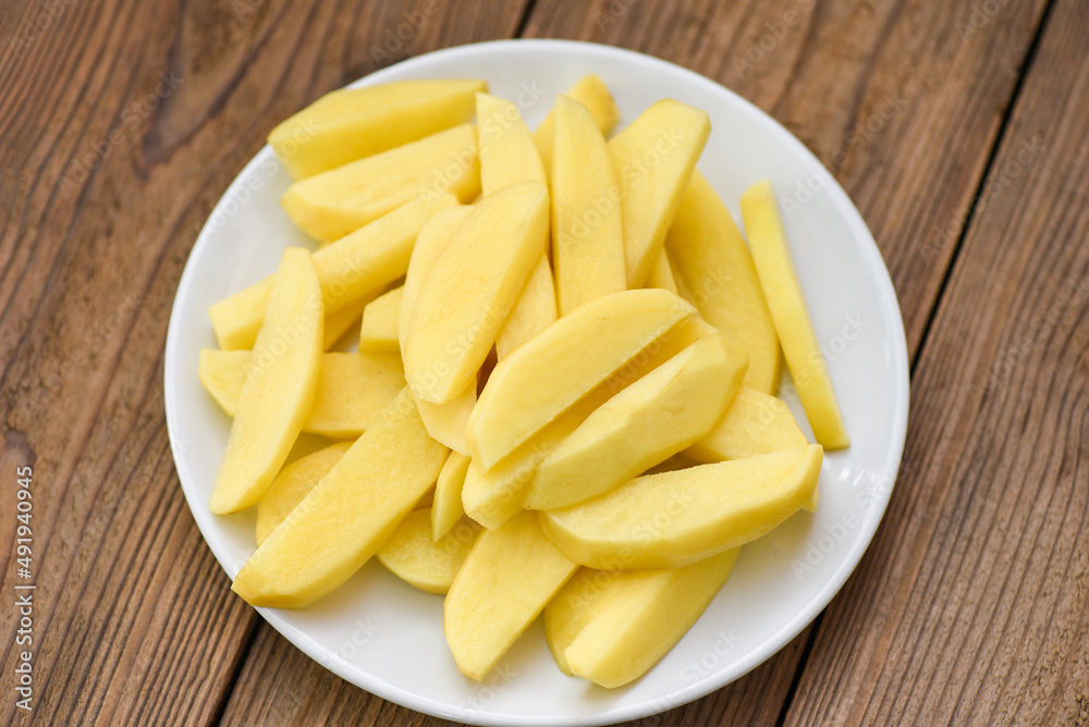 fresh raw potato wedges, chopped potatoes for cooked food on white plate fresh raw potato wedges, chopped potatoes for cooked food on white plate