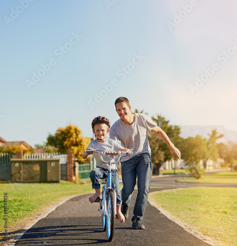 No training wheels needed. Shot of a father teaching his little son how to ride a bicycle in the park.