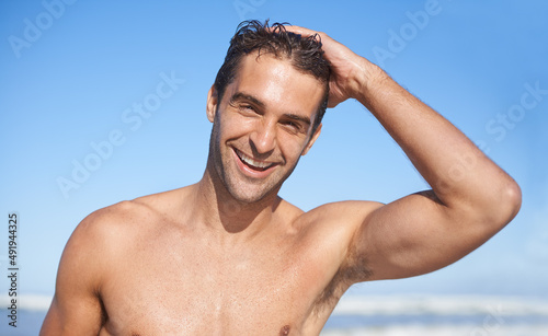 Handsome beach hunk. Head and shoulders shot of a gorgeous body guard running his fingers through his hair. photo