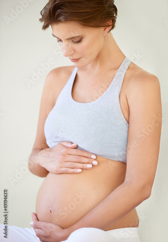 Great expectations. A beautiful young pregnant woman looking down at her bare tummy. Free Download Great expectations. A beautiful young pregnant woman looking down at her bare tummy. - GFXLoad