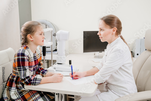 doctor interviews little girl before being examined in ophthalmologist s office.