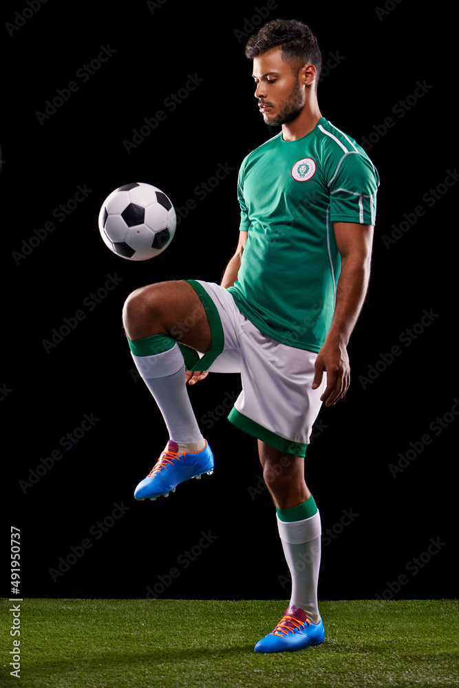 Perfect control. Full length studio shot of a handsome young soccer player isolated on black.