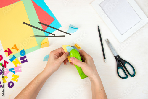 Women's hands are stapling paper circles with a stapler. Step by step instructions, top view. Step 12.