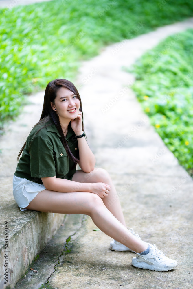 a portrait of beautiful happy asian woman traveler wearing brownish green dress stylish hipster Summer sunny lifestyle on the street outdoors at sunny summer day in park background