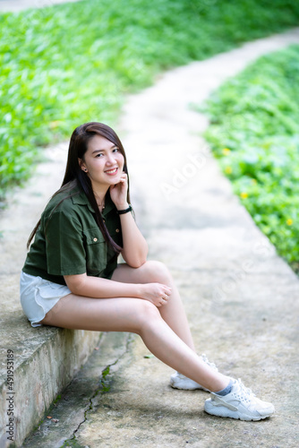 Obraz na płótnie a portrait of beautiful happy asian woman traveler wearing brownish green dress stylish hipster Summer sunny lifestyle on the street outdoors at sunny summer day in park background w salonie