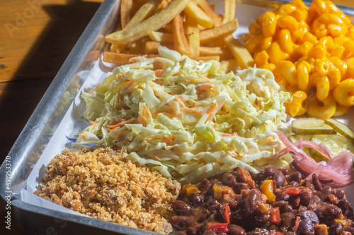 American barbecue tray with several garnishes, among them, coleslaw salad, Mac n cheese, barbecue beans, and french fries. photo