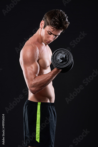 The best project youll ever work on is you. Studio shot of a young man working with dumbbells isolated on black.