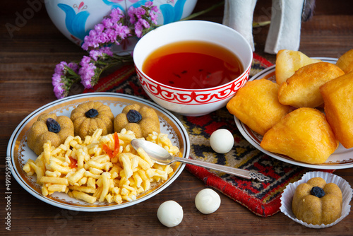 Kazakh still life on Nauryz, with national food: baursaks, zhent, kurt, chak chak and tea on a wooden background
