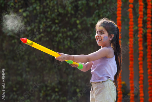 Little girl child celebrating Holi with pichkari photo