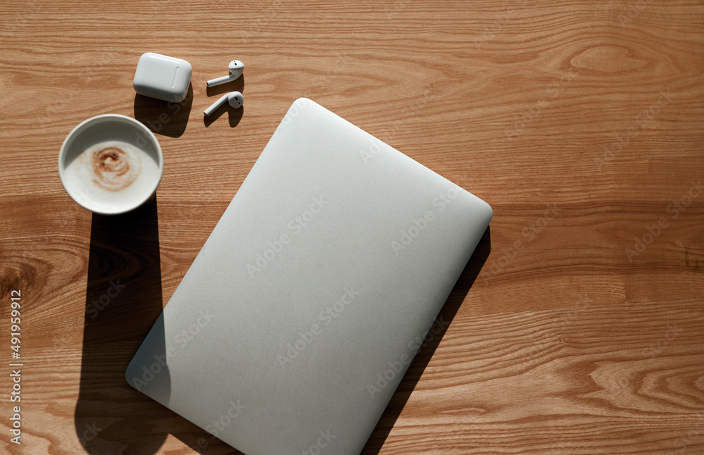 Laptop on wooden table with coffee and earbuds Laptop on wooden table with coffee and earbuds