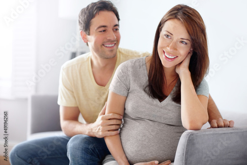 Showing his support all the way. Attractive young expecting couple sitting in their living room.