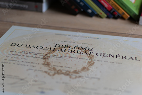 Baccalaureate : close up of a french diploma with some books, the text means general baccalaureate diploma