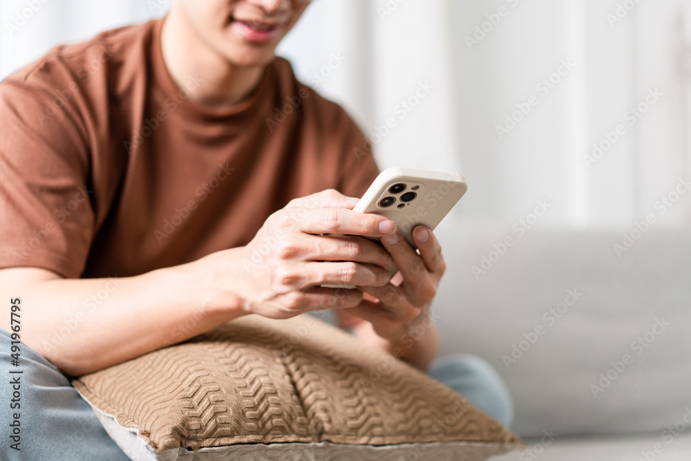 Technology Concept The man sitting next to a pot of plant, putting a small pillow on his lap, and checking something on his smartphone Technology Concept The man sitting next to a pot of plant, putting a small pillow on his lap, and checking something on his smartphone