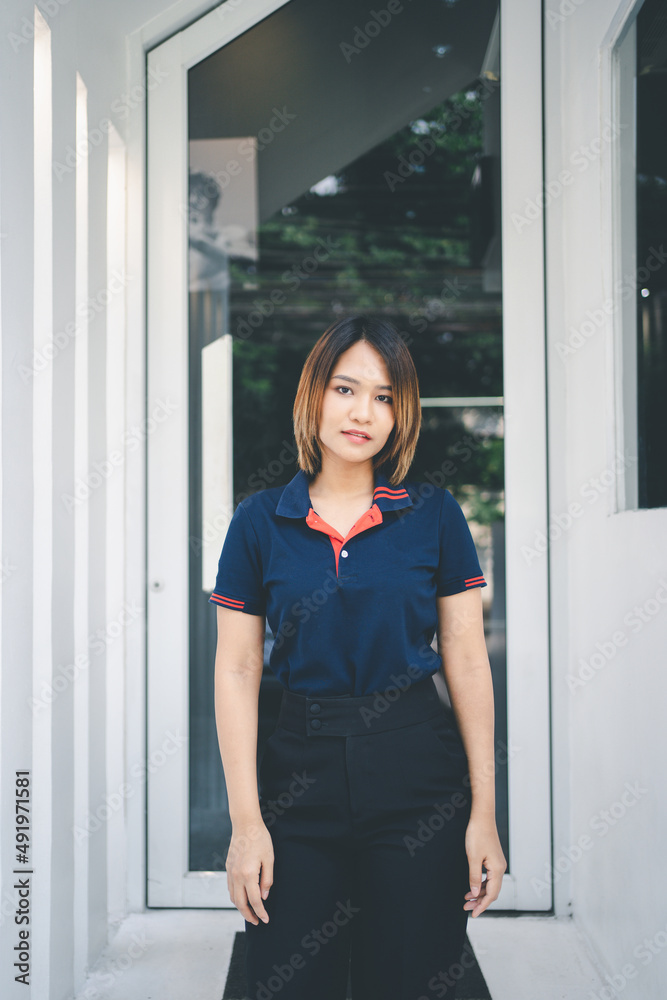 Happy asian woman standing outdoors in casual blue t shirt against cafe. Happy asian woman standing outdoors in casual blue t shirt against cafe.