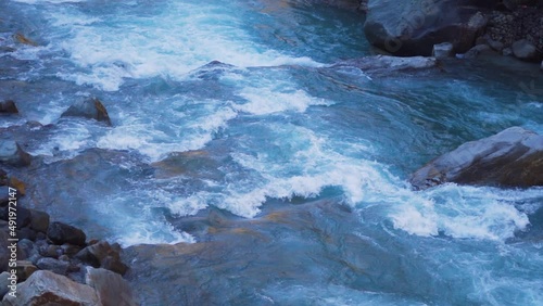 Slow motion shot of the Paravti River flowing in between mountains at Manikaran near Kasol in Himachal Pradesh, India. View of the Parvati river during the winter. Natural river in the mountains. photo