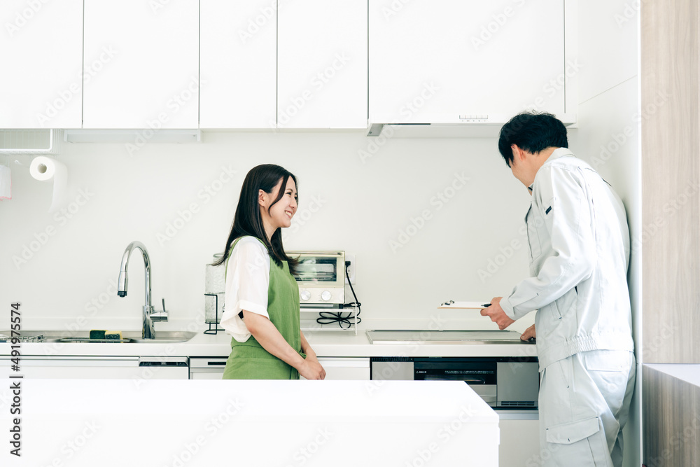 Fototapeta premium キッチンで話す作業着姿の男性と女性（IH・笑顔） 