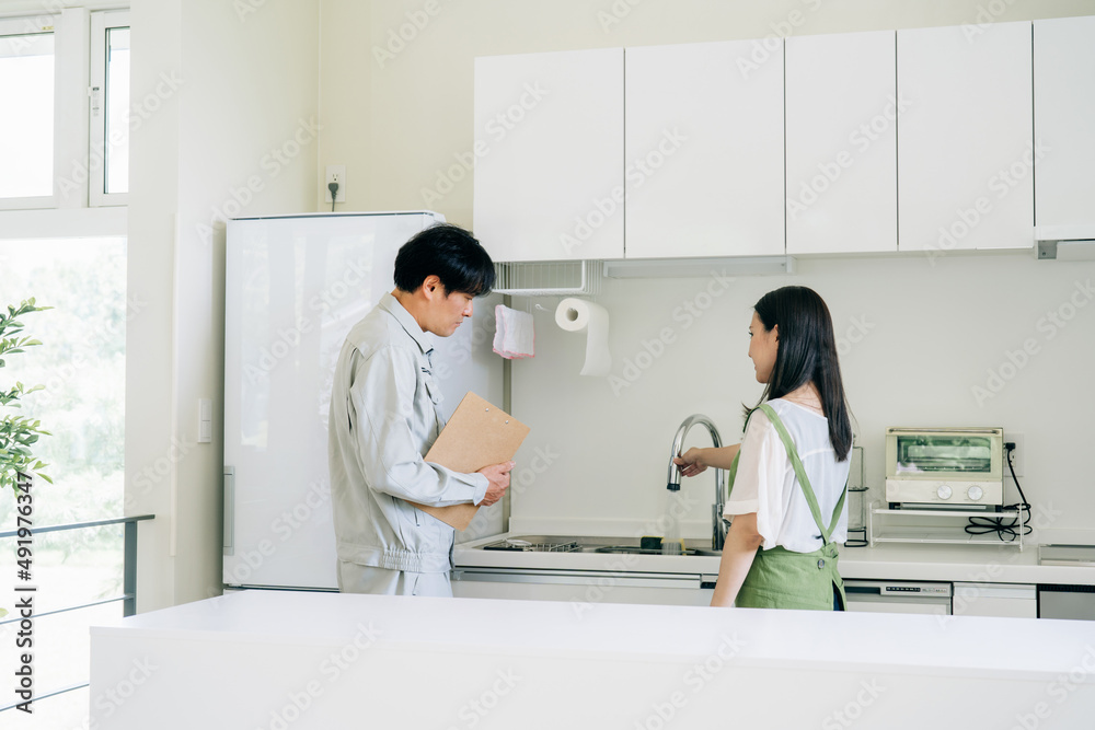 キッチンで話す作業着姿の男性と女性(水道・クレーム)
キッチンで話す作業着姿の男性と女性(水道・クレーム)