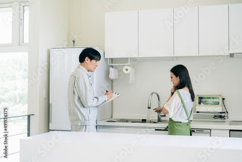 キッチンで話す作業着姿の男性と女性（水道・クレーム） 