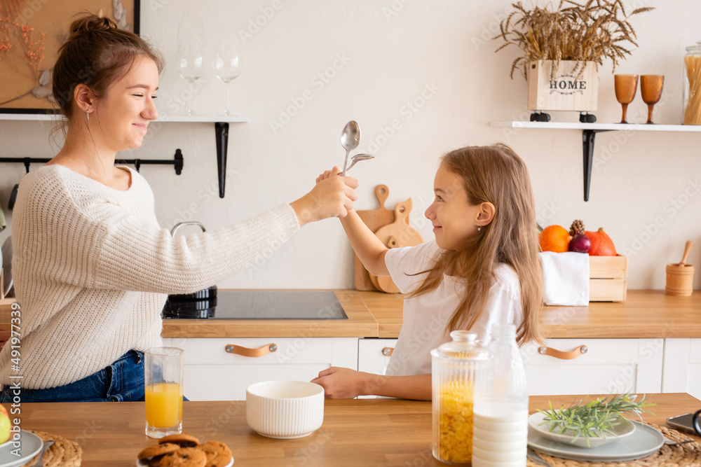 Portrait of two sisters having breakfast and talking. Girls play with