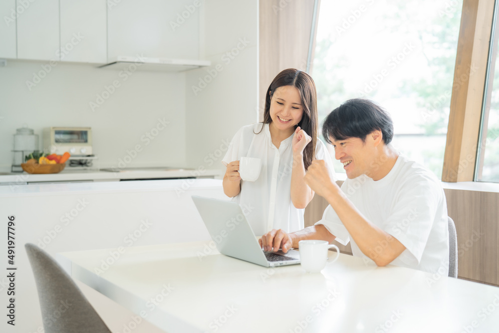 ダイニングでテレワークする男女(ガッツポーズ)
ダイニングでテレワークする男女(ガッツポーズ)