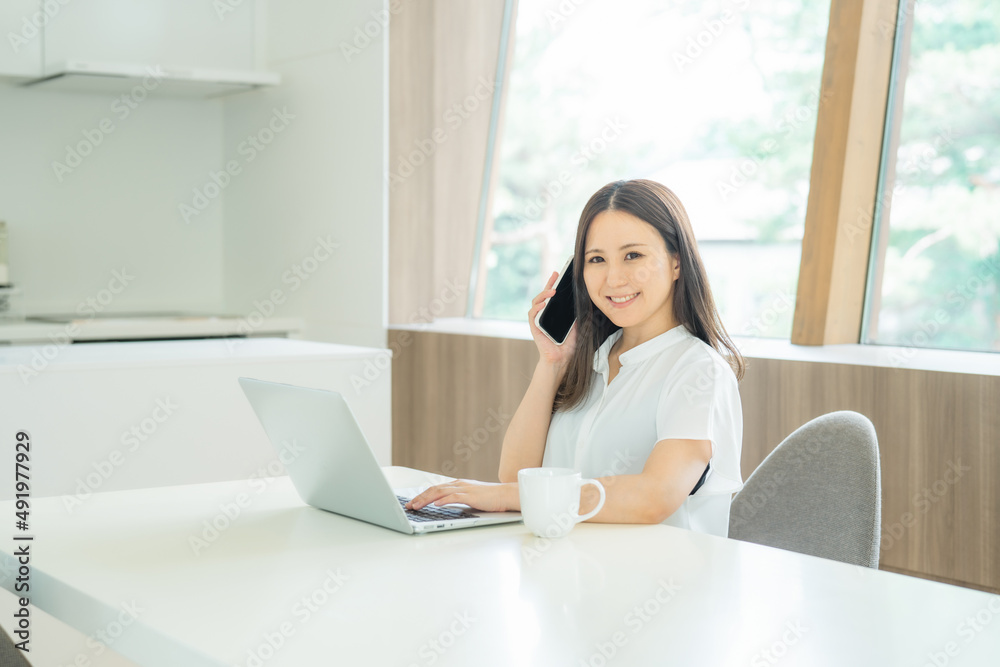 Obraz premium スマホとパソコンを使う女性