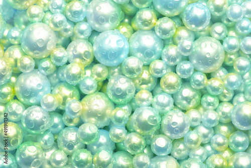Beautiful background green pearl pearls, top view. Abstract texture for festive backgrounds. Shiny surface of Christmas decorations. Gems close-up. Multicolored bright background.