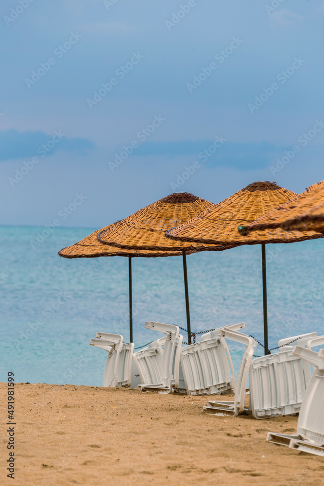 Beach straw umbrella on sunset by the sea, blue hour. amazing waves and clouds. 