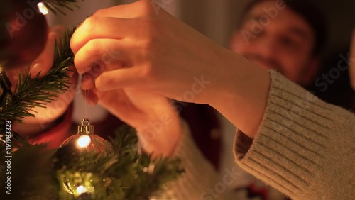winter holidays and people concept - happy couple decorating christmas tree at home in evening
