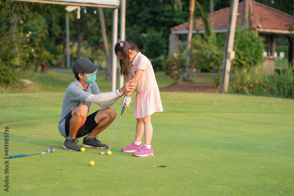 Obraz premium The older brother is teaching the sister to putt golf balls.