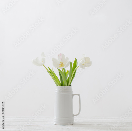 white tulips in jug on white background