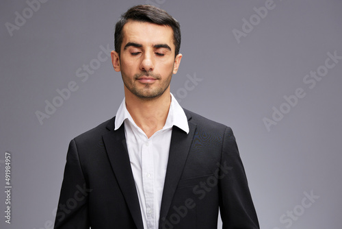 man with closed eyes in black business suit cropped view gray background copyspace