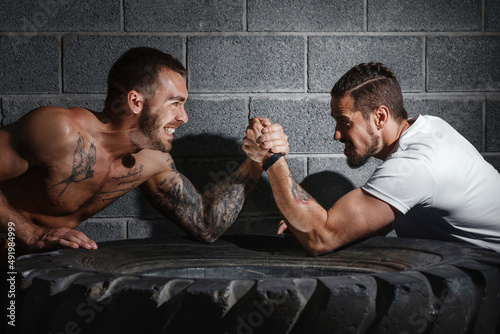 Two men with hands clasped in arm wrestling challenge. Bodybuilding concept photo