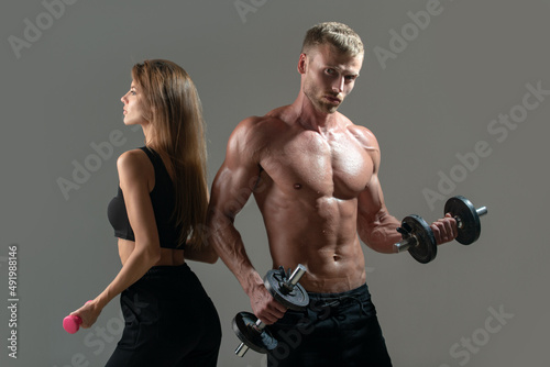 Couple of fit bodybuilders, muscular man and beautiful sexy girl with dumbbells. Muscular sexy couple body. Sport couple.