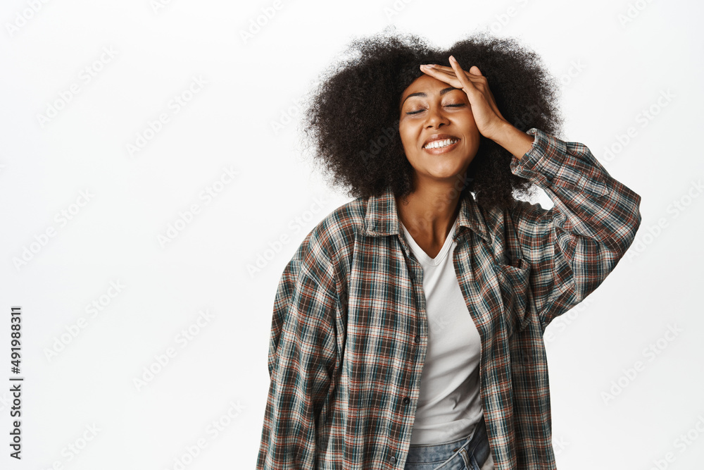 Portrait of carefree african woman shows happiness and joy, touches her healthy clear face, smiles upbeat, stands over white background Portrait of carefree african woman shows happiness and joy, touches her healthy clear face, smiles upbeat, stands over white background