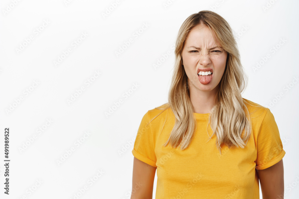 Dislike and aversion. Young woman grimaces and look with disgust at smth bad, stands over white background Dislike and aversion. Young woman grimaces and look with disgust at smth bad, stands over white background