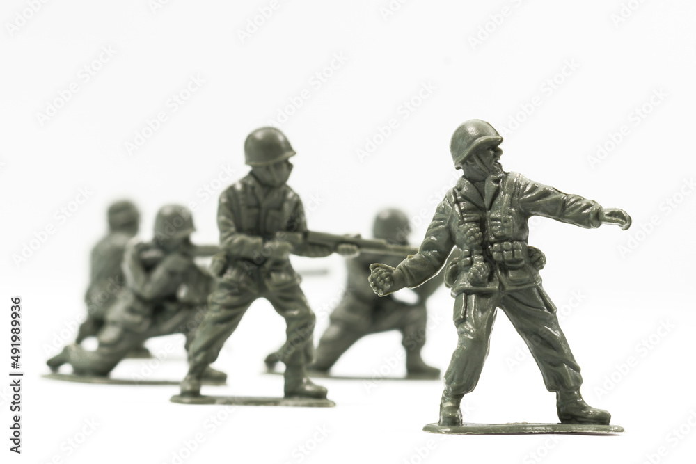 Plastic toy soldiers are arranged in a conflict situation and set against a white background. 