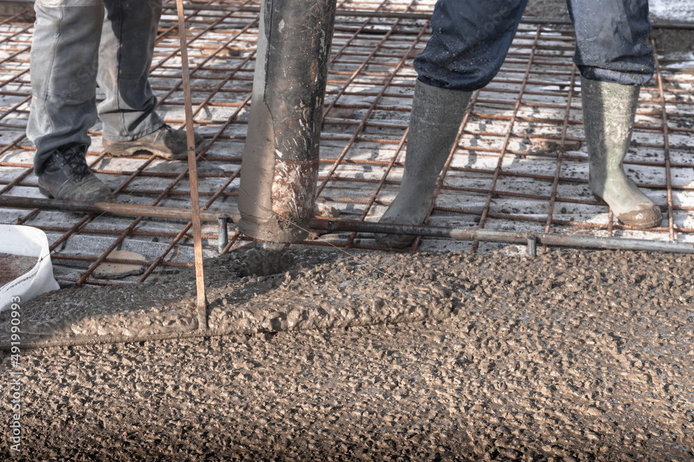 Foto de Builders workers pour concrete floor in industrial