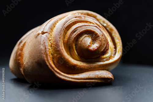 Fresh ruddy bun with jam on a black background. Close-up. Home bakery, food, cooking and pastry.