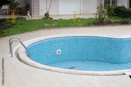 An empty pool in the backyard of the house