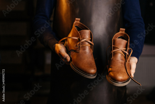 Photo of a pair of quality men's leather shoes in the hands of the master who made them.
