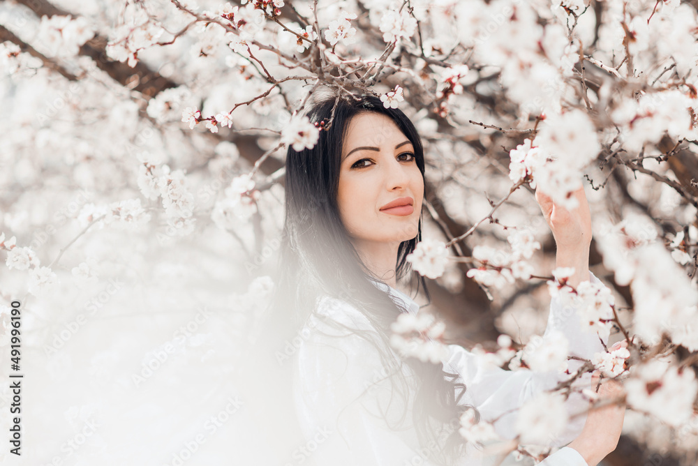 Portrait of pretty brunette girl posing against the spring blooming trees in the garden. Portrait of pretty brunette girl posing against the spring blooming trees in the garden.