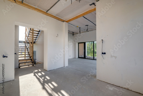 empty white room without repair and furniture with scaffolding with wooden stairs