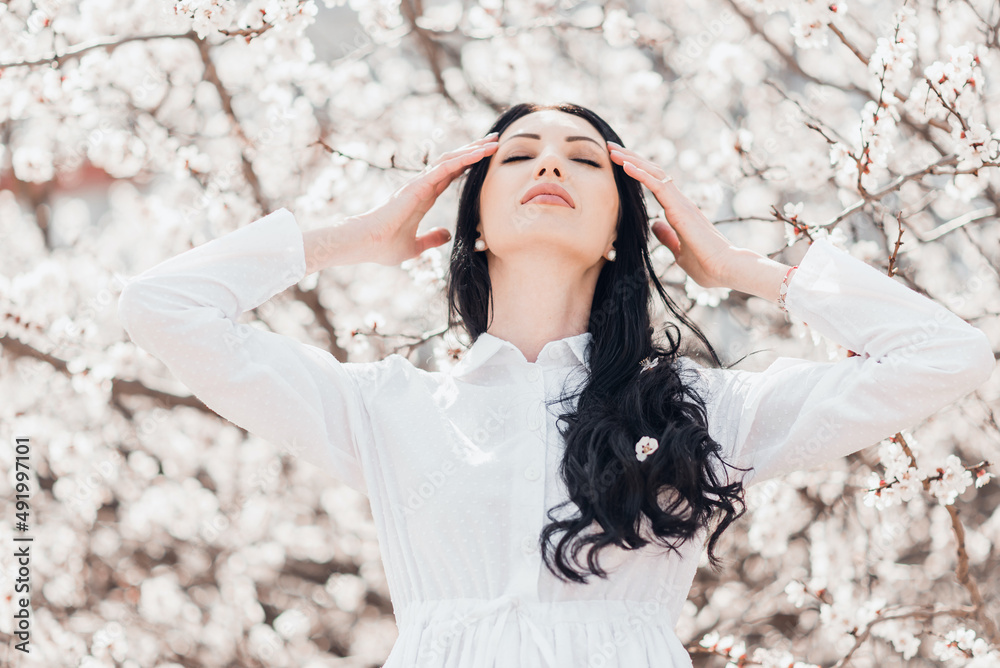 Portrait of pretty brunette girl posing against the spring blooming trees in the garden. Portrait of pretty brunette girl posing against the spring blooming trees in the garden.
