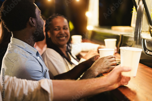 Multiracial people having fun drinking in counter at food truck restaurant outdoor - Focus on man ear