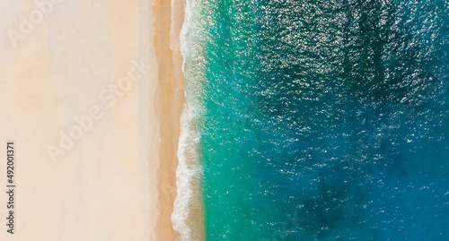 Top-down aerial view of a clean white sandy beach on the shores of a beautiful turquoise sea